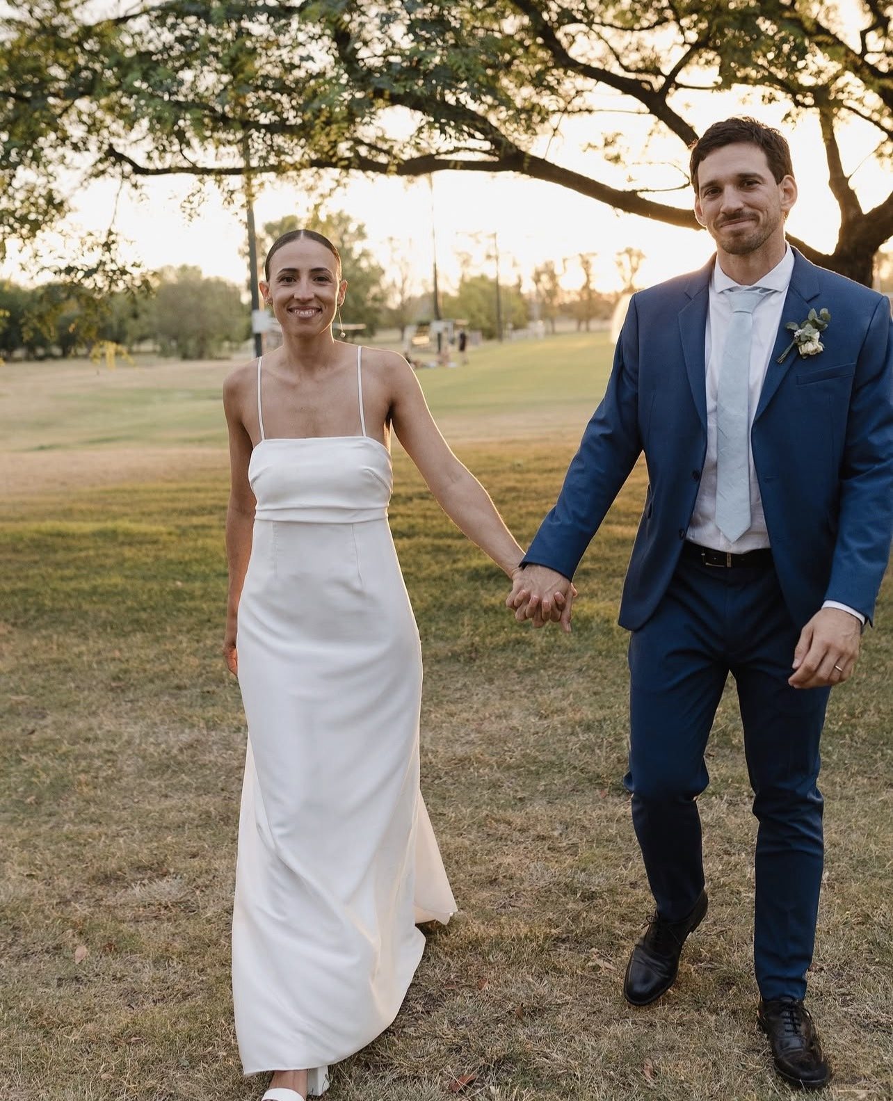 Novios recién casados caminando de la mano al atardecer en un golf de Buenos Aires